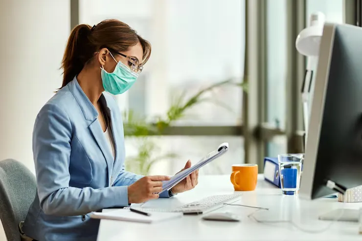 A woman reviewing patient reports at a desk.